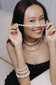 Young woman holding strand of pearls - Asia Images Group