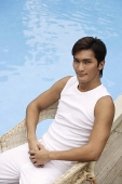 Young man sitting poolside - Asia Images Group