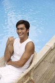 Young man sitting poolside - Asia Images Group