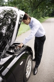 Businessman looking under hood of car - Asia Images Group