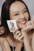 Young woman holding joker card - Asia Images Group