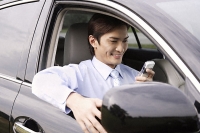 Man smiling while reading message on hand held device - Asia Images Group