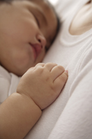 baby girl sleeping against woman's chest - Asia Images Group