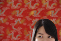 Cropped face of Chinese woman standing against Chinese silk background - Asia Images Group