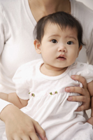 Baby girl being held on woman's lap - Asia Images Group