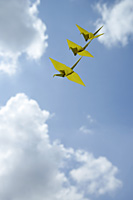 3 yellow paper cranes against sky backdrop - Asia Images Group