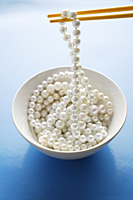 string of pearls on chopstick - Asia Images Group