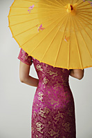 young Chinese woman in pink cheongsam holding yellow umbrella - Asia Images Group