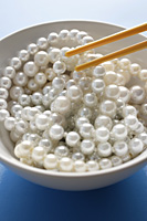 chopsticks picking a strand of pearls from a bowl - Asia Images Group