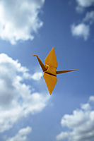 single yellow paper crane against sky backdrop - Asia Images Group