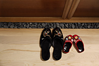 top view of red and black oriental slippers at door front - Asia Images Group