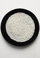 uncooked grains of rice spread out on a black plate - Asia Images Group