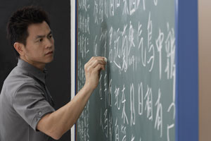 man writing Chinese characters on chalk board - Asia Images Group