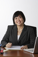 business woman sitting at desk smiling - Asia Images Group