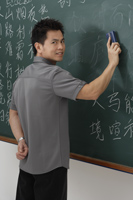 man erasing Chinese characters on chalk board - Asia Images Group