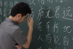 man thinking in front of Chinese characters on chalk board - Asia Images Group