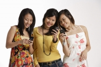 Three women looking at hand phones. - Asia Images Group