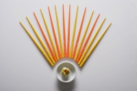 Orange and yellow chopsticks lined up over dim sum. - Asia Images Group