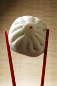 close up of red chop sticks holding steamed bun - Asia Images Group