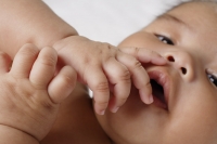 Close up of hands on babies mouth. - Asia Images Group
