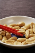close up of red chopsticks picking up peanuts - Asia Images Group