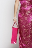 Cropped shot of woman in pink cheongsam holding shopping bag - Asia Images Group