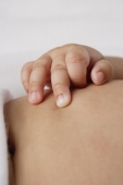 Close up of babies hand on tummy. - Asia Images Group