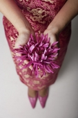 close up of woman wearing pink cheongsam holding purple flower - Asia Images Group
