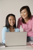 Two women at laptop, smiling. - Asia Images Group