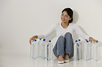 Young Asian woman sitting with water bottles - Asia Images Group