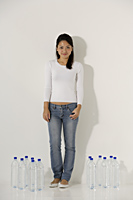 Young Asian woman standing near water bottles - Asia Images Group