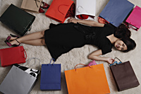 Chinese woman laying on floor with shopping bags - Asia Images Group