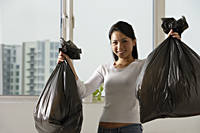 Young Asian woman holding up trash bags - Asia Images Group