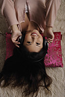 Chinese woman laying on floor listening to music - Asia Images Group