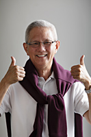 mature man with grey hair holding thumbs up and smiling - Asia Images Group