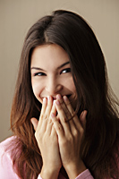 young woman laughing while covering her mouth with her hands - Asia Images Group