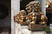 Row of bronze statues in front of Buddhist temple. - Asia Images Group