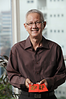 mature man holding red envelopes "hong bao" - Asia Images Group