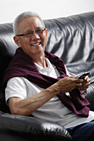 mature man with grey hair smiling holding a phone - Asia Images Group