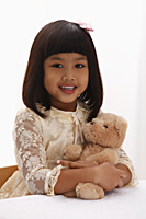 young girl holding teddy bear and smiling - Asia Images Group