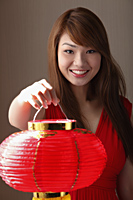 Young woman holding red lantern and smiling - Asia Images Group