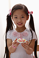 young girl with pony tails holding cookies - Asia Images Group