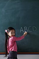 young girl writing on chalk board - Asia Images Group