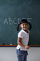 Young girl smiling in front of chalk board - Asia Images Group