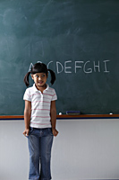 young girl standing in front of the chalkboard smiling - Asia Images Group