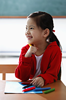 Young girl holding crayon and smiling - Asia Images Group