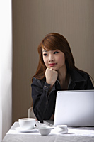 Young woman sitting at table with laptop - Asia Images Group