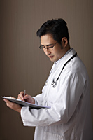 Profile of male doctor holding clipboard - Asia Images Group