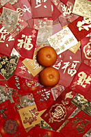 Many different red envelopes, Hong Bao scattered on table with oranges. - Asia Images Group