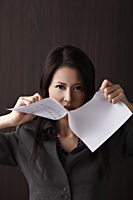 Head shot of woman ripping paper - Asia Images Group